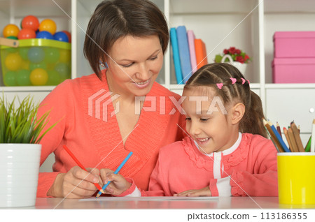 Mom and daughter draw at home together. Mom and daughter draw at home together. 113186355