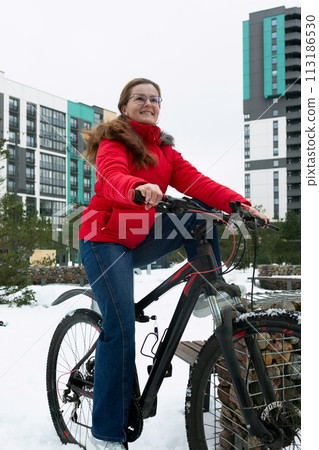 Active European woman pedaling a bicycle in winter 113186530