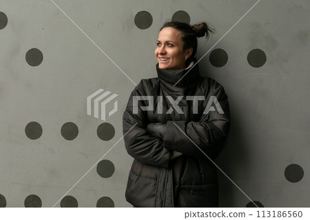 Portrait of a happy cute brunette woman against a black wall 113186560