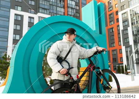 A young man in autumn clothes walks with a bicycle around the city A young man in autumn clothes walks with a bicycle around the city 113186642