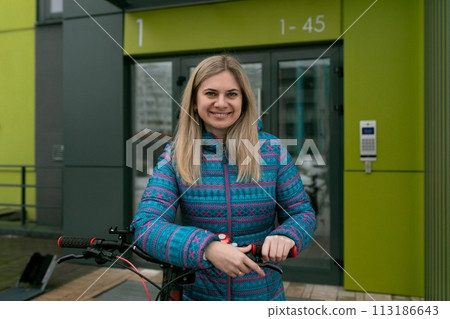 Lifestyle concept. Woman in a blue jacket walking with a bicycle Lifestyle concept. Woman in a blue jacket walking with a bicycle 113186643
