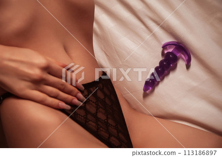 silicone butt anal plug next to woman girl with a sexy body in underwear lies on bed in bedroom. Female sex toys for anal sex and orgasm silicone butt anal plug next to woman girl with a sexy body in underwear lies on bed in bedroom. Female sex toys for anal sex and orgasm 113186897