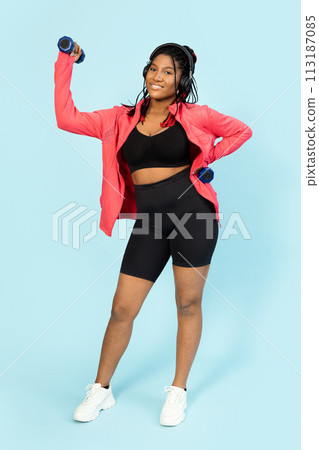 Active Woman Exercising with Dumbbells and Enjoying Music 113187085