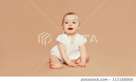 Happy cute baby crawling on the floor on brown studio background Happy cute baby crawling on the floor on brown studio background 113188009