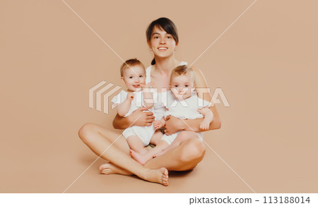 Happy cheerful smiling young mother holding baby on brown background Happy cheerful smiling young mother holding baby on brown background 113188014
