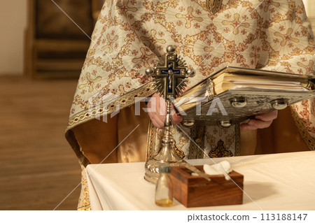 A priest in a cassock prays and reads the bible 113188147