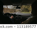 Back view of unrecognizable man and a woman driving car on a country road, roadtrip concept 113189577