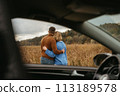 View through the car window, a man and a woman are embracing each other, adult couple enjoying their road trip 113189578