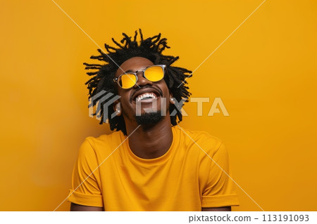 A man with a yellow shirt and sunglasses is smiling 113191093