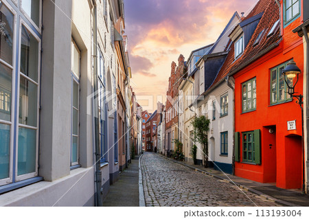 Scenic view old narrow european german Lubeck town street red brick ancient houses vintage iron stained glass lamp lantern on wall. Cityscape UNESCO heritage city altstadt Germany travel destination Scenic view old narrow european german Lubeck town street red brick ancient houses vintage iron stained glass lamp lantern on wall. Cityscape UNESCO heritage city altstadt Germany travel destination 113193004