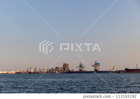 Ships float across the North Sea. Windmills in the background. Sea port in the Netherlands. A lot of cranes for loading goods. Different ships and barges. Ships float across the North Sea. Windmills in the background. Sea port in the Netherlands. A lot of cranes for loading goods. Different ships and barges. 113193192