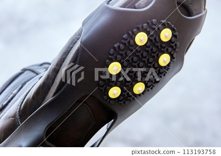 Overlay anti-slip spikes on soles of winter shoes to improve traction and prevent slipping during icy conditions. 113193758