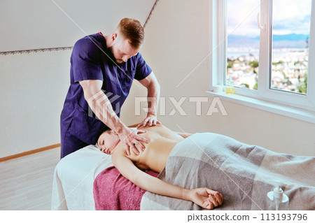 Massage therapist brought massage table to young woman home to give her back massage. 113193796
