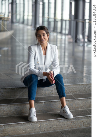 Smiling relaxed pretty woman sitting on the steps Smiling relaxed pretty woman sitting on the steps 113194314