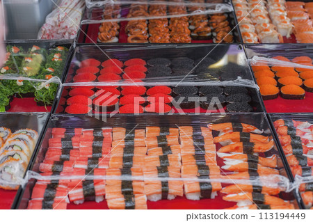 Various sushi sale on street market. Sushi with caviar, red salmon, shrimps, mussels, Hiyashi Wakame seaweed salad 113194449