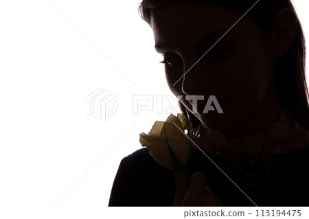 Young woman sniffs a flower - horizontal side view silhouette 113194475