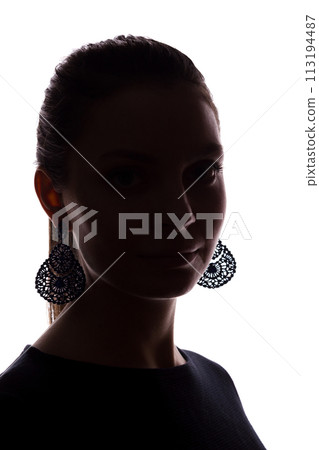 Young girl with earrings looks straight ahead, portrait isolate silhouette 113194487