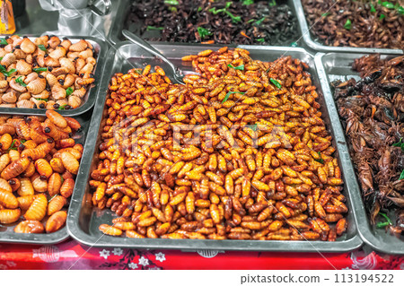 Thai food deep fried spicy silk worms at night street market in Phuket, Thailand 113194522