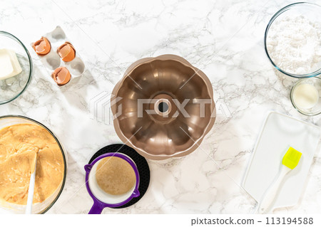 Using a silicone brush, the metal bundt cake pan is greased with melted vegetable shortening, preparing for baking the scrumptious Carrot Bundt Cake. 113194588