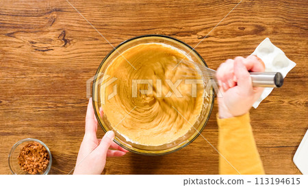 Flat lay. In a glass mixing bowl, a large hand whisk expertly blends the ingredients for a delectable gingerbread bundt cake with caramel frosting. 113194615