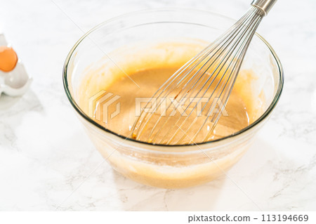 In a large glass bowl, the ingredients are expertly mixed to create the batter for baking the scrumptious Carrot Bundt Cake. 113194669