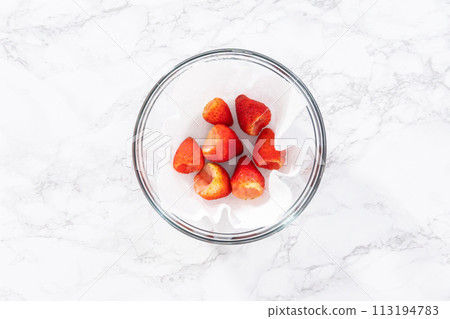 Freshly washed and dried strawberries are carefully arranged in a glass bowl lined with paper towel, ready for snacking or further use. 113194783