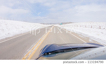 Navigating a frontage road post-winter storm offers a serene drive. The surrounding landscape, blanketed in snow, contributes to the peaceful and picturesque environment, enhancing the driving 113194790