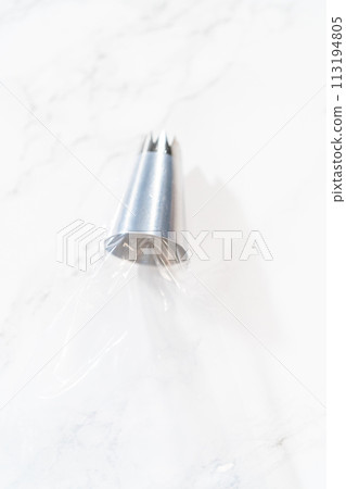 The chocolate icing is carefully transferred into a piping bag, ready to adorn the scrumptious cupcakes. The chocolate icing is carefully transferred into a piping bag, ready to adorn the scrumptious cupcakes. 113194805