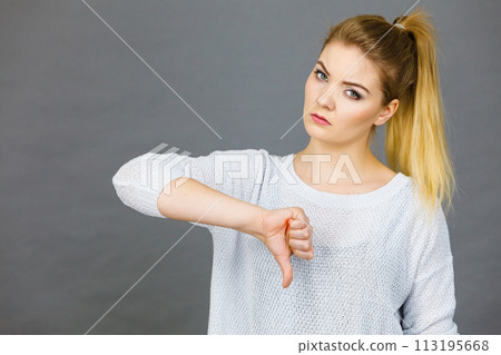Sad woman showing thumb down gesture Sad woman showing thumb down gesture 113195668