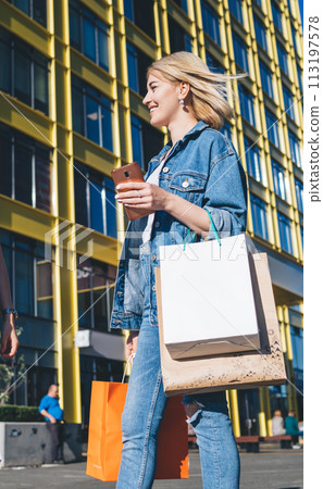 Trendy women with shopping bags in urban district 113197578