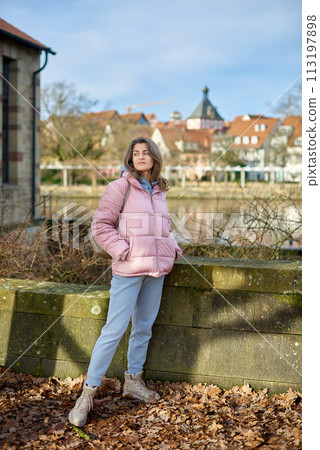 Young beautiful pretty tourist girl in warm hat and coat with backpack walking at cold autumn in Europe city enjoying her travel in Bietigheim-Bissingen, Deutschland. Outdoor portrait of young tourist Young beautiful pretty tourist girl in warm hat and coat with backpack walking at cold autumn in Europe city enjoying her travel in Bietigheim-Bissingen, Deutschland. Outdoor portrait of young tourist 113197898