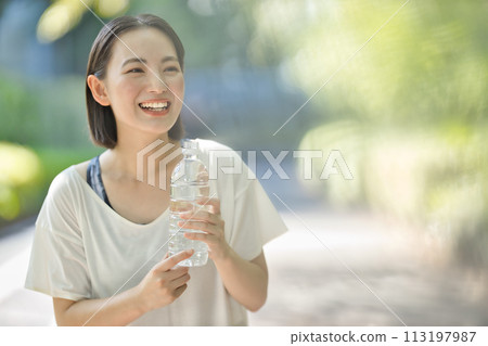 穿著運動服的年輕女子用塑膠瓶喝水 113197987