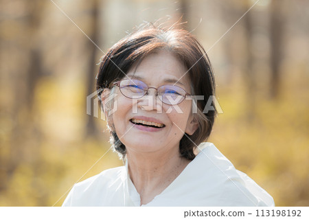 Close-up of a senior woman with a natural cheerful smile outdoors in backlit autumn and winter. Beauty, health, etc. 113198192