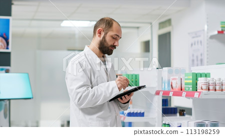 Healthcare workers monitoring pharmaceutical packs on racks and managing store inventory to guarantee clients are provided with goods. Pharmacy technician handling pills boxes logistics. 113198259