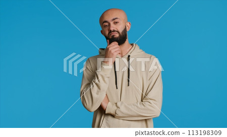 Middle eastern person thinking about a thing on camera, acting pensive and puzzled while trying to make a decision. Arab guy acting thoughtful and unsure about a question. Camera 1. 113198309