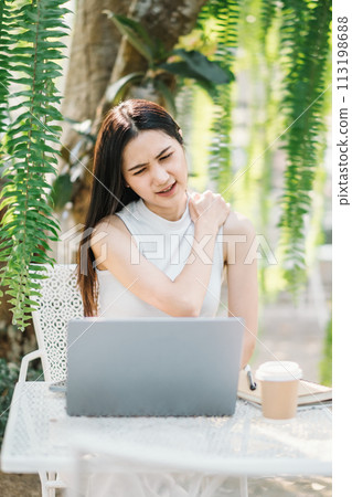 Woman takes a relaxing break from work, enjoying the tranquil environment of an outdoor garden cafe. 113198688