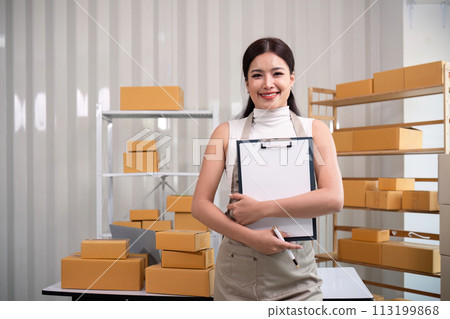Young business woman asian working online ecommerce shopping at her shop. Young woman sell prepare parcel box of product for deliver to customer. Online selling 113199868