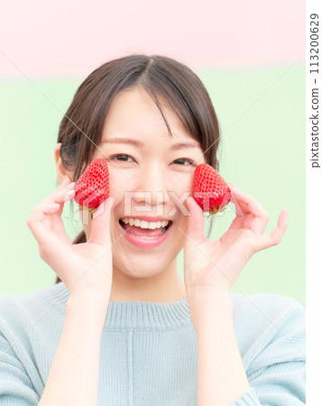 Smiling young woman holding strawberries in her hands Smiling young woman holding strawberries in her hands 113200629