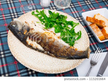 Grilled sea bass fish served with arugula 113201664