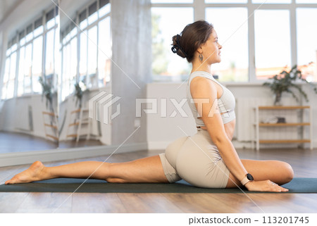Positive young girl performing stretching asana Ardha Kapotasana 113201745