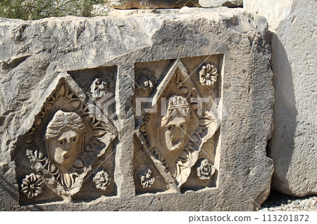 Historical stone bas-relief with carved faces in ancient city of Myra on sunny day. Dead civilization. Ruins of rock tombs in Lycia region, Demre, Antalya, Turkiye Historical stone bas-relief with carved faces in ancient city of Myra on sunny day. Dead civilization. Ruins of rock tombs in Lycia region, Demre, Antalya, Turkiye 113201872