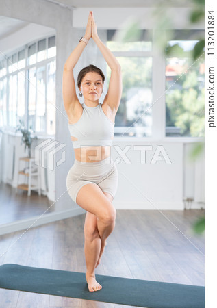 Lover of active lifestyle on yoga mat perform doing Garudasana in gym 113201884