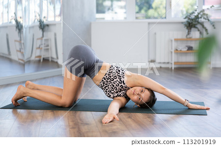 Sporty young woman doing yoga in studio, performing hamstring and low back stretching Ardha Pawanmuktasana Sporty young woman doing yoga in studio, performing hamstring and low back stretching Ardha Pawanmuktasana 113201919