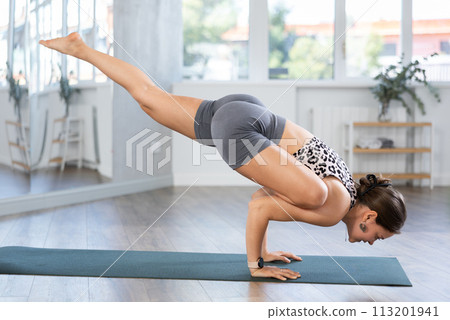 Active young woman in activewear practicing crow pose yoga at yoga studio Active young woman in activewear practicing crow pose yoga at yoga studio 113201941