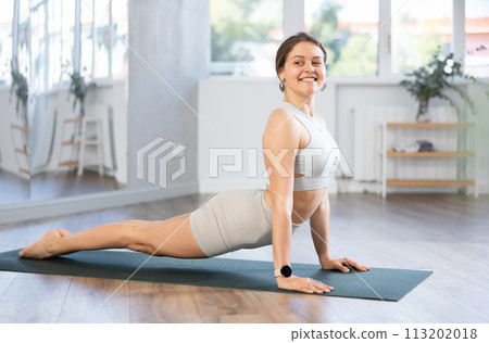 Smiling girl doing stretching asana Urdhva Mukha Shvanasana 113202018