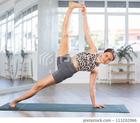 Young woman performing powerful Side Plank Pose with raised leg Young woman performing powerful Side Plank Pose with raised leg 113202066