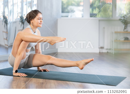 Yoga in sports gym. Girl performs bacasana asana Yoga in sports gym. Girl performs bacasana asana 113202091