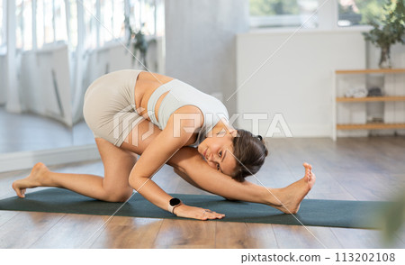 Young positive coach girl in activewear doing stretching exercises during training yoga in sports club Young positive coach girl in activewear doing stretching exercises during training yoga in sports club 113202108