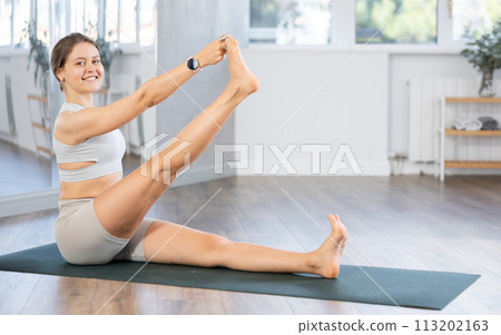 Portrait of young sporty woman making stretching legs and yoga pose at sports club Portrait of young sporty woman making stretching legs and yoga pose at sports club 113202163