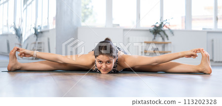 Young woman practicing yoga in supta kurmasana pose 113202328